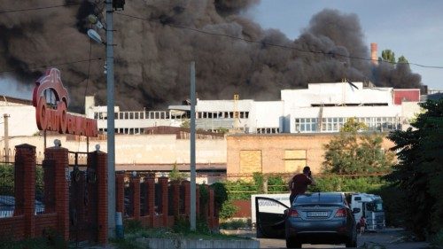 A man observes a cloud of smoke in the background after a missile strike on a warehouse of an ...