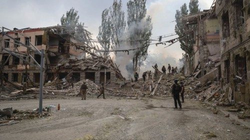 Rescuers and servicemen work at a school building damaged by a Russian military strike, amid ...