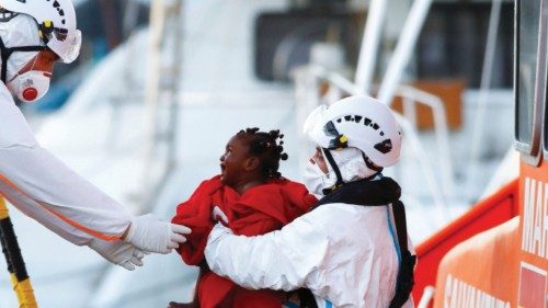 Rescuers help a migrant child to disembark from a Spanish coast guard vessel, in the port of ...