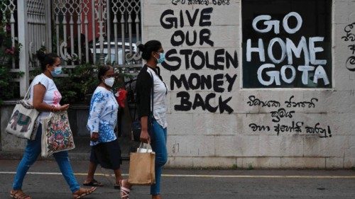 CORRECTION / A man rides a bicycle walk past slogans painted on a wall against the government near ...