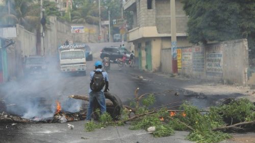 A man holds a tire at a road block as demonstrators blocked streets to protest ongoing fuel ...