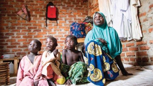 A 21-year-old Cameroonian mother named Aïcha Mahamat Amina and her children sit and look on at the ...