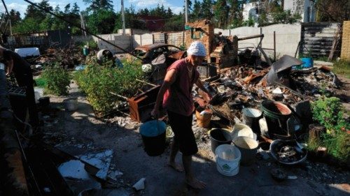 Valentyna, 75, carries buckets with water at her house destroyed as a result of shelling in village ...