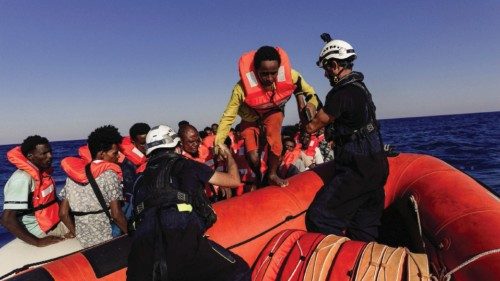 Sea-Watch crew member helps a migrant boarding a dinghy in the Mediterranean Sea, July 23, 2022. ...