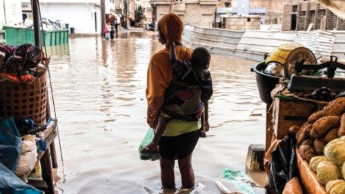 A woman carries her child and shopping through a flooded street market after Dakar?s first major ...