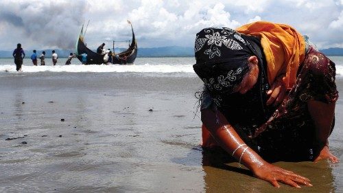 FILE PHOTO: An exhausted Rohingya refugee woman touches the shore after crossing the ...