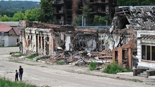 TOPSHOT - Pedestrians walk past destroyed buildings in the city of Trostyanets, Sumy region on ...
