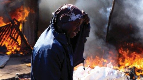 A man reacts as he attempts to extinguish a burning shack after community members burned shacks and ...