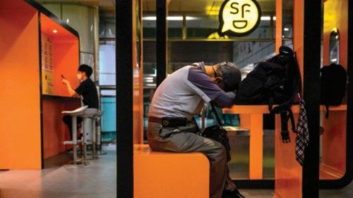 A man sleeps at a cubicle in an area for relaxing, charging electronic device batteries or desk ...