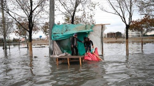 Vendors stand in their stall on a flooded street after a heavy rainfall in Kabul on November 15, ...