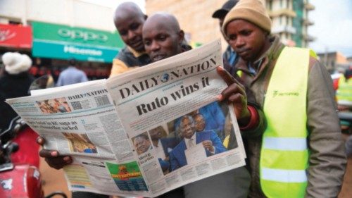 Motorcycle riders read the Daily Nation, a local daily newspaper, with a headline reporting the ...