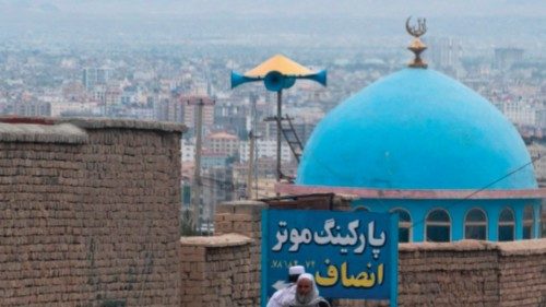 Afghan men walk past the blue dome of a mosque a day after the blast in the outskirts of Kabul ...