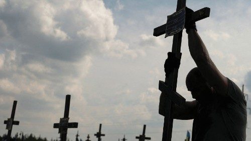 A volunteer places a cross with a number to a grave of one of unidentified persons killed by Russian ...