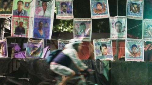 A person rides past a wall with pictures of some of the 43 students who disappeared from the ...