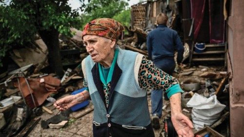 TOPSHOT - An eldery woman stands outside her heavily damaged house after it was hit by a missile in ...