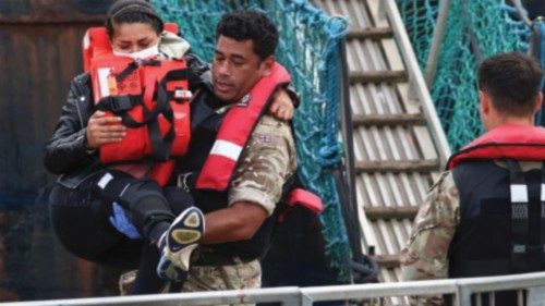 A migrant is carried into Dover harbour by a member of the military, after being rescued while ...