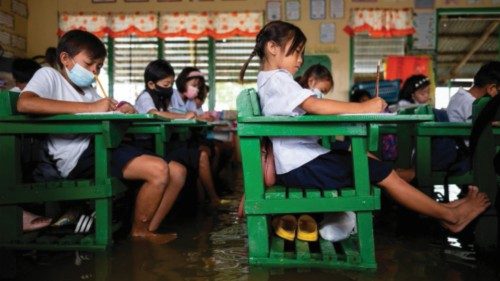 Students attend the first day of in-person classes, at a flooded school due to high tide, in ...