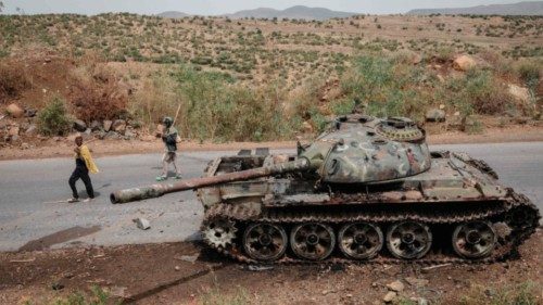 (FILES) In this file photo taken on June 20, 2021 Local farmers walk next to a tank of alledged ... (FILES) In this file photo taken on June 20, 2021 Local farmers walk next to a tank of alledged ...