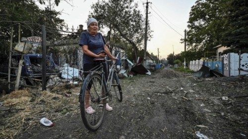 A woman stands near residential houses destroyed by a Russian military strike, as Russia's attack on ...