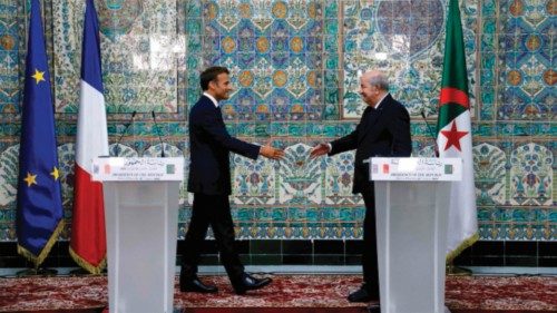 French President Emmanuel Macron (L) and Algeria's President Abdelmadjid Tebboune (R) shake hands at ...