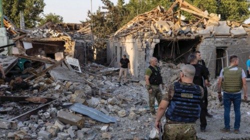 Police and military officers inspect destroyed houses by a strike, amid Russia's invasion, in ...