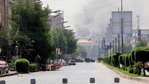 Smoke billows in the background in the capital Baghdad during an army-imposed nationwide curfew on ...