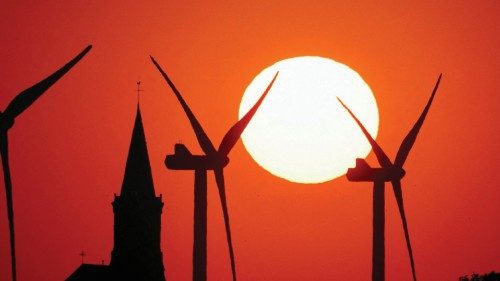 FILE PHOTO: Power-generating windmill turbines and the church of the village are pictured during ...