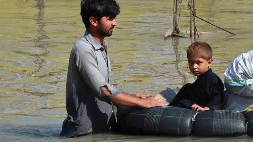 A family wades through a flood hit area following heavy monsoon rains in Charsadda district of ...