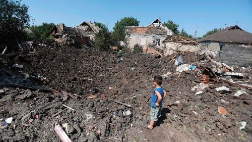 A boy looks at a crater following a strike in Druzhkivka village, Donetsk region on August 17, 2022, ...