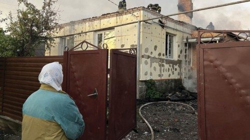 A local resident looks at Ukrainian firefighters put out fire in a residential house after a Russian ...