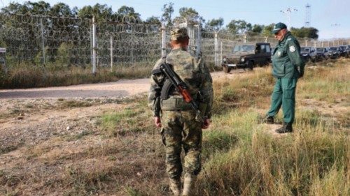 Bulgarian border police personnel stand near the fence, built across the Bulgarian-Turkish border, ...