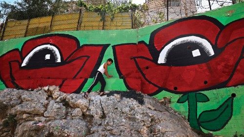 A boy plays near a mural painted as part of a public art project entitled 'I witness Silwan' ...