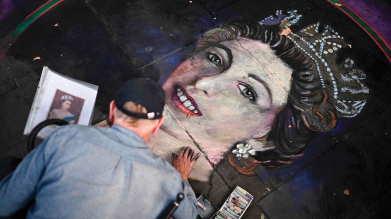 TOPSHOT - An artist draws a portrait of Britain's Queen Elizabeth II on tiles with chalk at ...