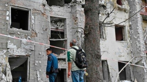 Local residents stand outside their building partially destroyed by a missile strike on Kharkiv on ...
