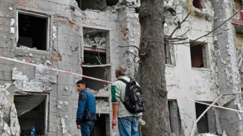 Local residents stand outside their building partially destroyed by a missile strike on Kharkiv on ... Local residents stand outside their building partially destroyed by a missile strike on Kharkiv on ...