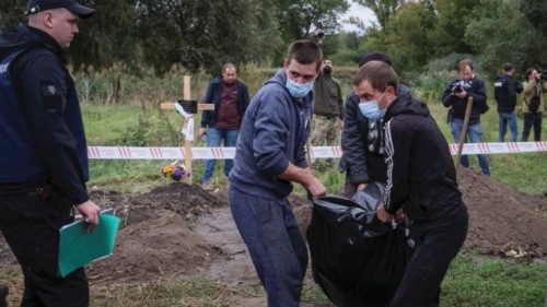 A police officer looks on as workers carry the body of a person who, according to Ukrainian police, ...