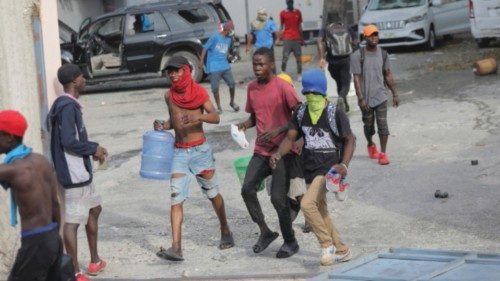 People run after looting a business during protests over rising fuel prices and crime as inflation ...