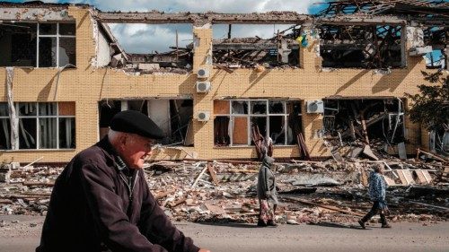 TOPSHOT - People walk past a destroyed building in Kupiansk, Kharkiv region, on September 19, 2022, ...