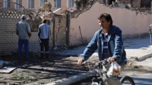 A man rides a bicycle past the ruins of a building destroyed by recent shelling during ...