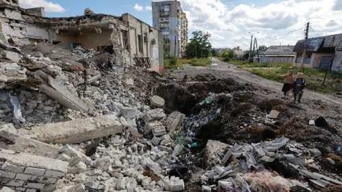 Local residents stand next to the debris of a destroyed building in the course of Russia-Ukraine ...