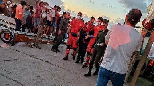 People take part in the rescue process of migrants in the port of Tartous, Syria September 22, 2022 ...