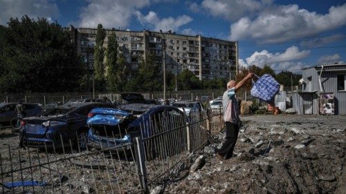 A man stands next to a crater left by a Russian missile strike, amis Russia's attack on Ukraine, in ...
