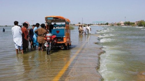 FILE PHOTO: Displaced people stand on flooded highway, following rains and floods during the monsoon ...