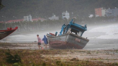 TOPSHOT - Children play next to a beached boat following the passage of typhoon Noru in Danang on ...