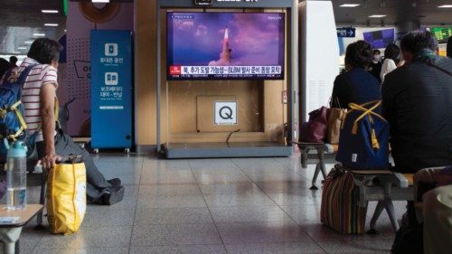 epa10214811 Commuters watch the news about a North Korea ballistic missile launch, at a station in ...