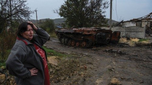 A woman stands next to a destroyed armoured fighting vehicle in the liberated village of Kamianka, ...