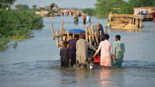 Men walk along a flooded road with their belongings, following rains and floods during the monsoon ...