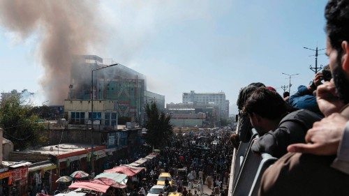 People watch smoke billowing from a fire at a business centre mall in Kabul on October 5, 2022. ...