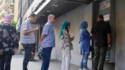 epa10228641 People line up at an ATM machine outside a closed bank covered with metal sheets, in ...