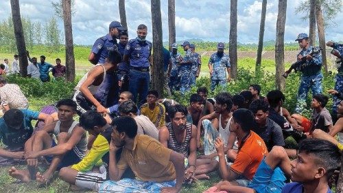 Members of Bangladesh security personnel stand guard beside Rohingya refugees rescued from the sea ...